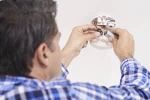 A man repairing a smoke detector. 