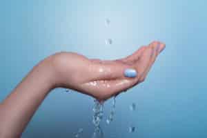 Water falling in drops and spilling over a cupped hand.