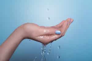 Water falling in drops and spilling over a cupped hand. 