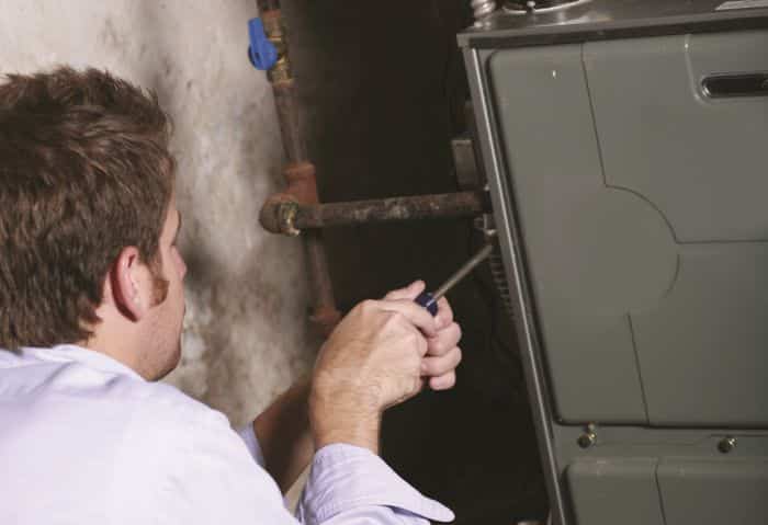 Heating repair technician working on a furnace.