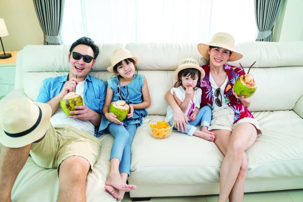 Family on a couch with summer hats and coconut drinks